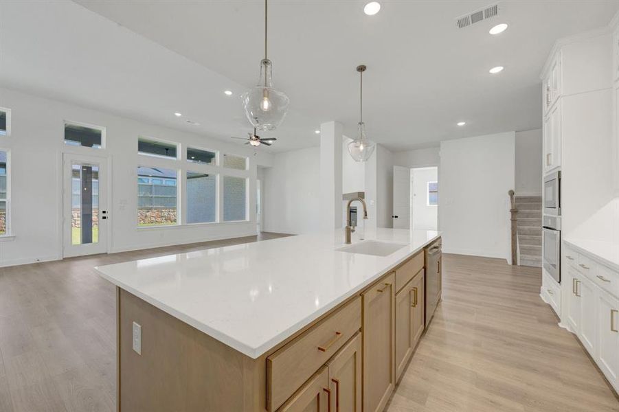 Spacious kitchen island featuring a white countertop, undermount sink, and two pendant lights
