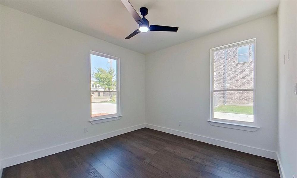 Empty room with dark wood-style floors and ceiling fan