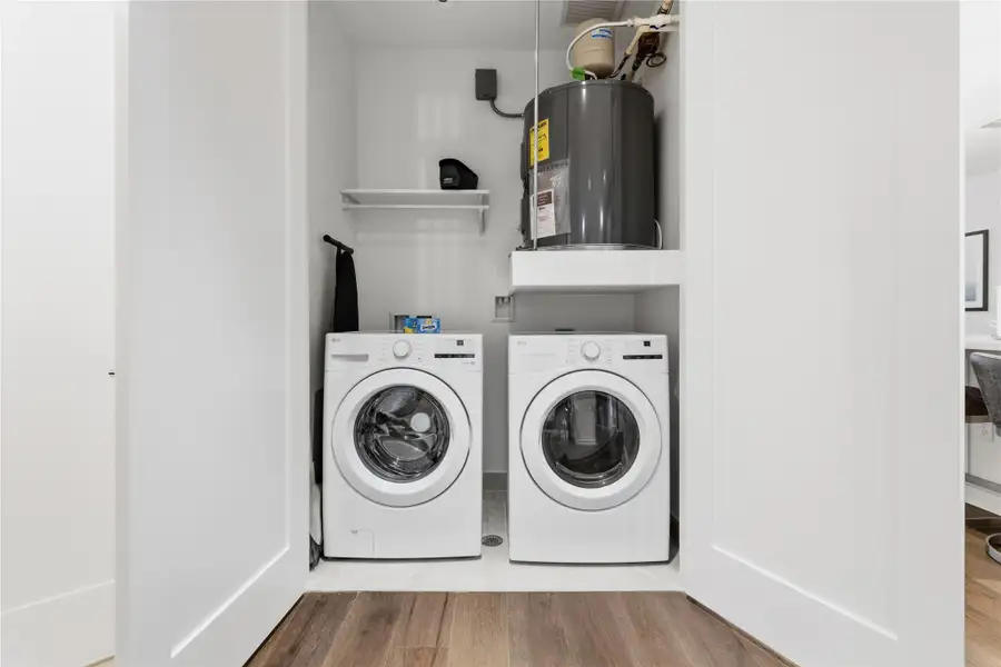 Laundry area featuring water heater, wood finished floors, and washer and clothes dryer