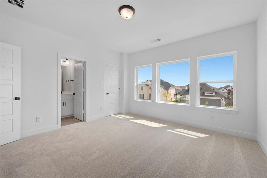 Unfurnished bedroom with light carpet and ensuite bathroom