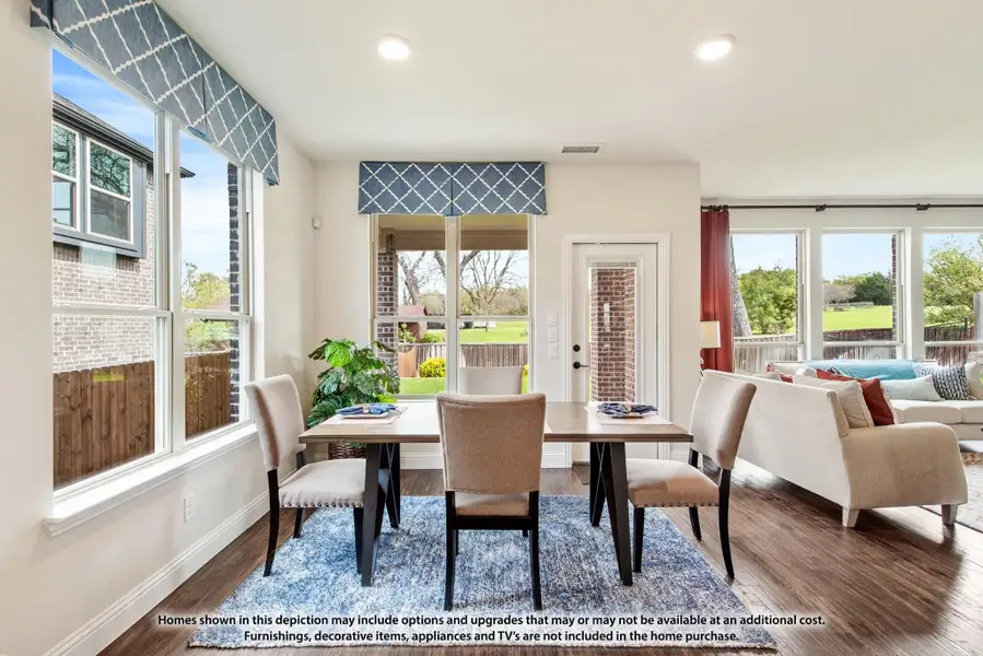 Dining area with wood table, upholstered chairs, blue area rug, and large windows with patterned valances