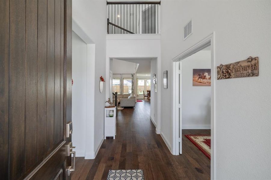 Entrance foyer with a high ceiling, dark wood finished floors, visible vents, and baseboards