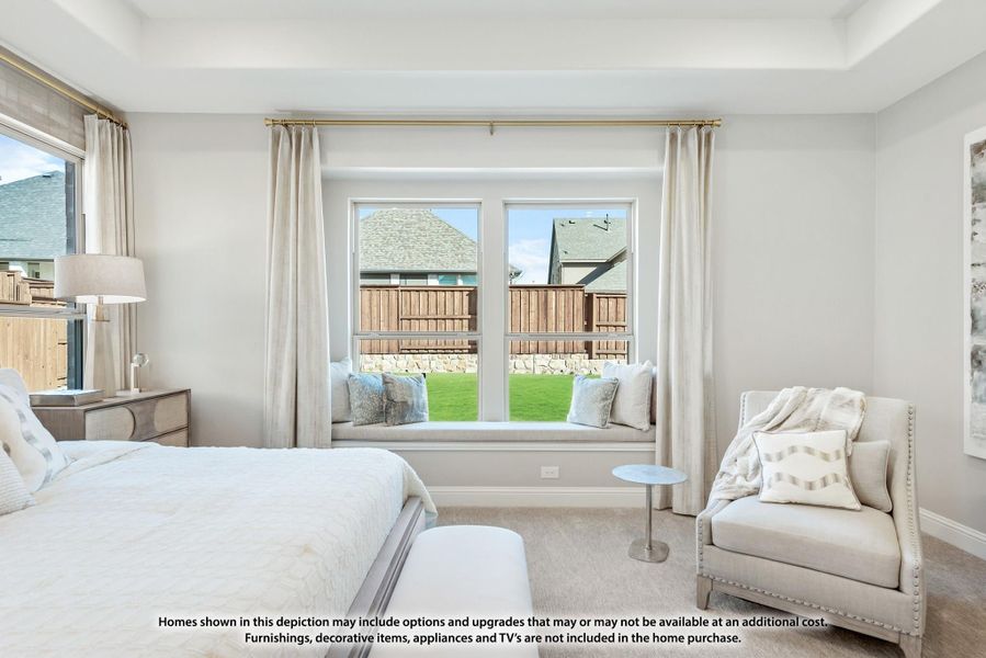 Bedroom with tray ceiling, built-in window seat, neutral carpet, and backyard view through large windows Bedroom with tray ceiling, built-in window seat, neutral carpet, and backyard view through large windows
