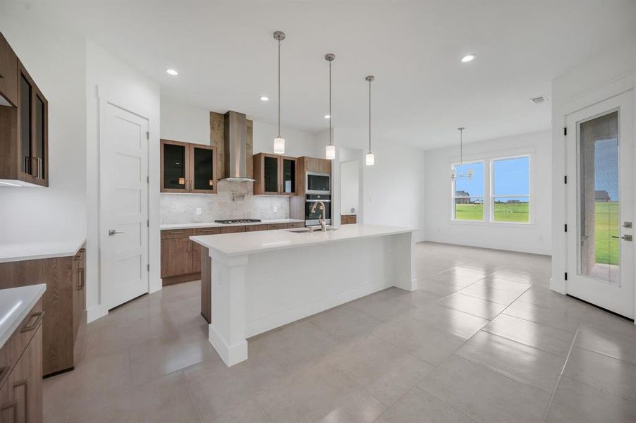 Kitchen with backsplash, light countertops, a sink, stainless steel appliances, and wall chimney exhaust hood Kitchen with backsplash, light countertops, a sink, stainless steel appliances, and wall chimney exhaust hood