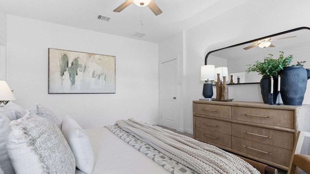 Primary bedroom with ceiling fan, plush carpeting, and a large walk-in closet.