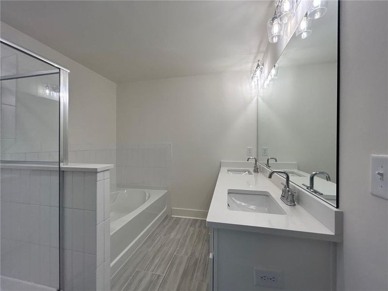 Bathroom with tile flooring, a bath to relax in, and dual bowl vanity