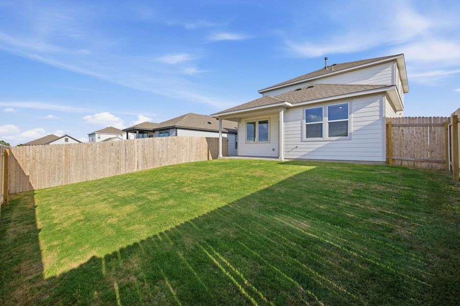 A well-maintained lawn provides ample space for outdoor activities, enclosed by a sturdy wooden fence.