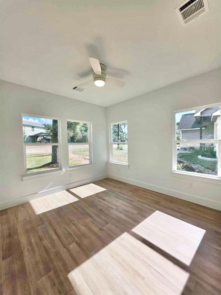 Unfurnished room with wood finished floors, healthy amount of natural light, and ceiling fan
