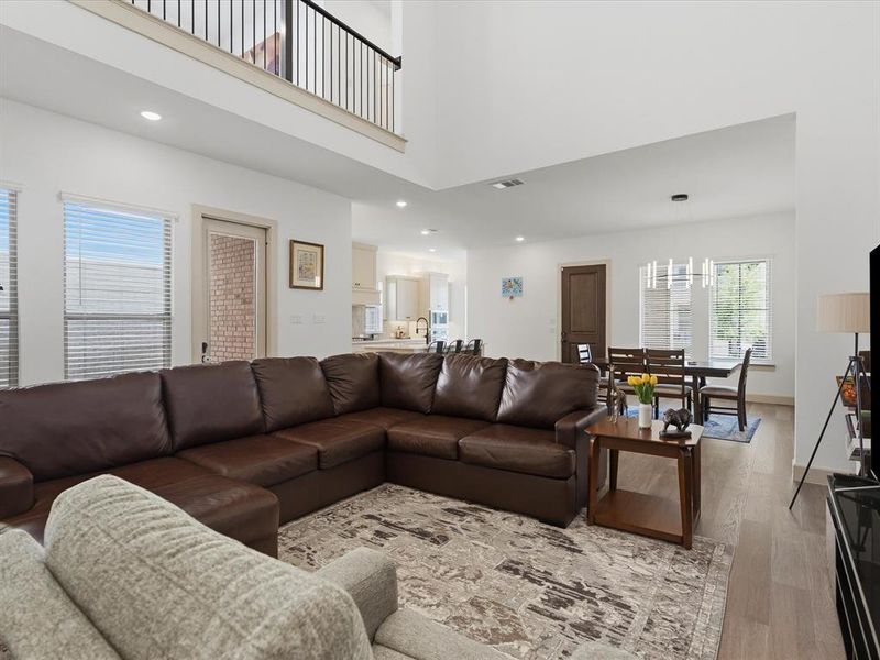 Open-concept living space featuring high ceilings, wood-finish flooring, and recessed lighting