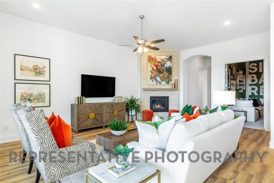 Living room featuring a large fireplace, recessed lighting, wood finished floors, arched walkways, and ceiling fan Living room featuring a large fireplace, recessed lighting, wood finished floors, arched walkways, and ceiling fan