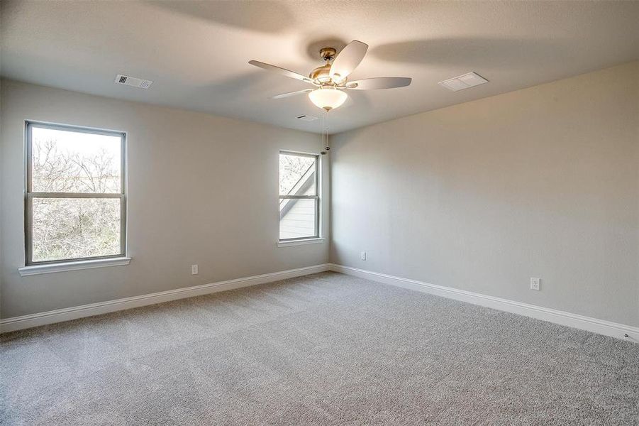 Unfurnished room with light colored carpet and ceiling fan Unfurnished room with light colored carpet and ceiling fan