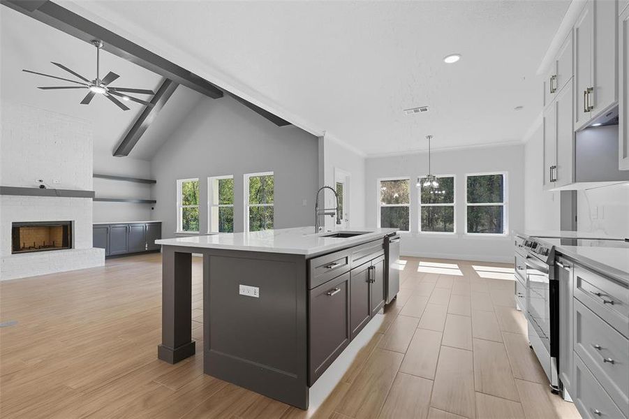 Kitchen featuring open floor plan, electric range, a kitchen island with sink, decorative light fixtures, and beamed ceiling Kitchen featuring open floor plan, electric range, a kitchen island with sink, decorative light fixtures, and beamed ceiling
