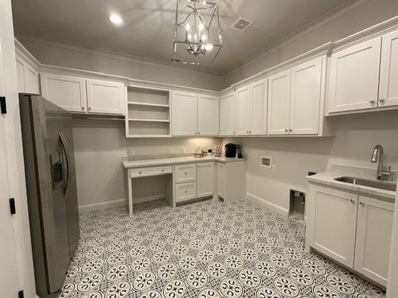 Washroom with hookup for a washing machine, sink, ornamental molding, cabinets, and a chandelier