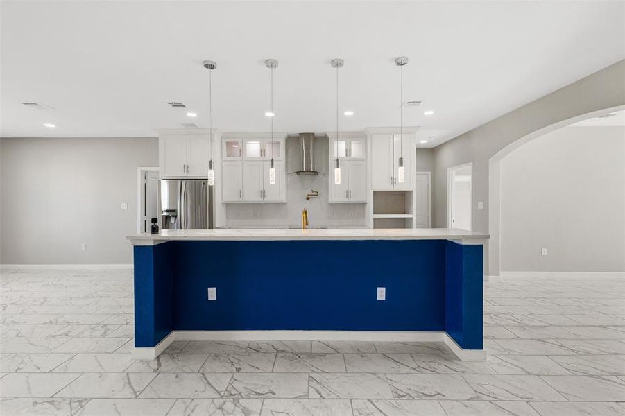Kitchen with white cabinets, glass insert cabinets, pendant lighting, arched walkways, and stainless steel fridge with ice dispenser