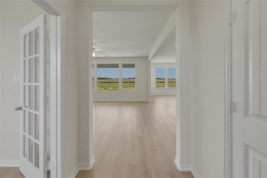 Entryway featuring a paneled interior door, a glass-paned French door, wood-finish flooring, and white baseboards Entryway featuring a paneled interior door, a glass-paned French door, wood-finish flooring, and white baseboards