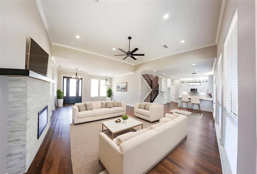 Living area featuring a chandelier, crown molding, stairs, dark wood finished floors, and a glass covered fireplace Living area featuring a chandelier, crown molding, stairs, dark wood finished floors, and a glass covered fireplace