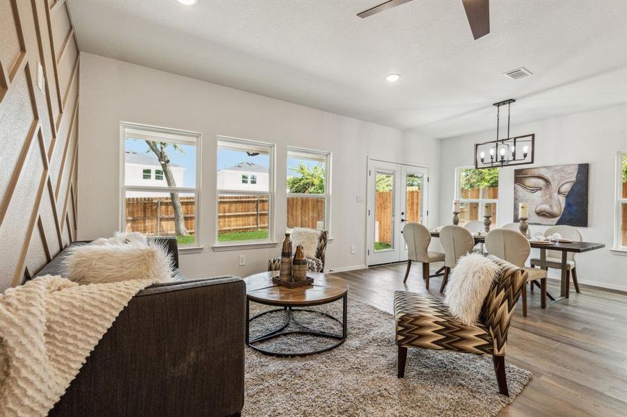 Living room featuring wood-type flooring, ceiling fan with notable chandelier, and plenty of natural light