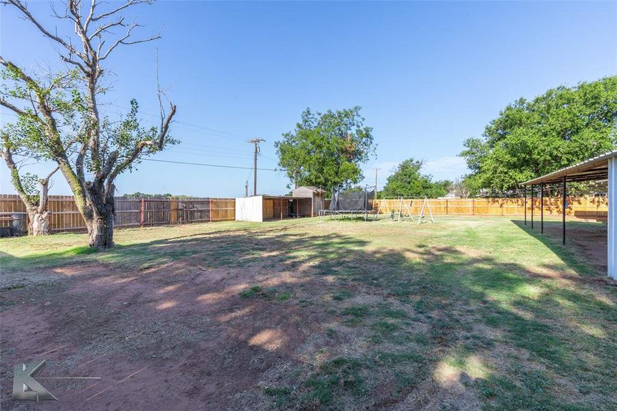 Fenced backyard with a trampoline and a storage unit