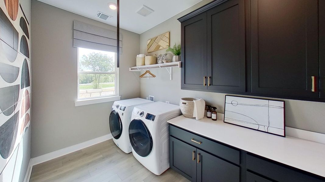 Laundry area with light wood-type flooring, washer and clothes dryer, and cabinet space
