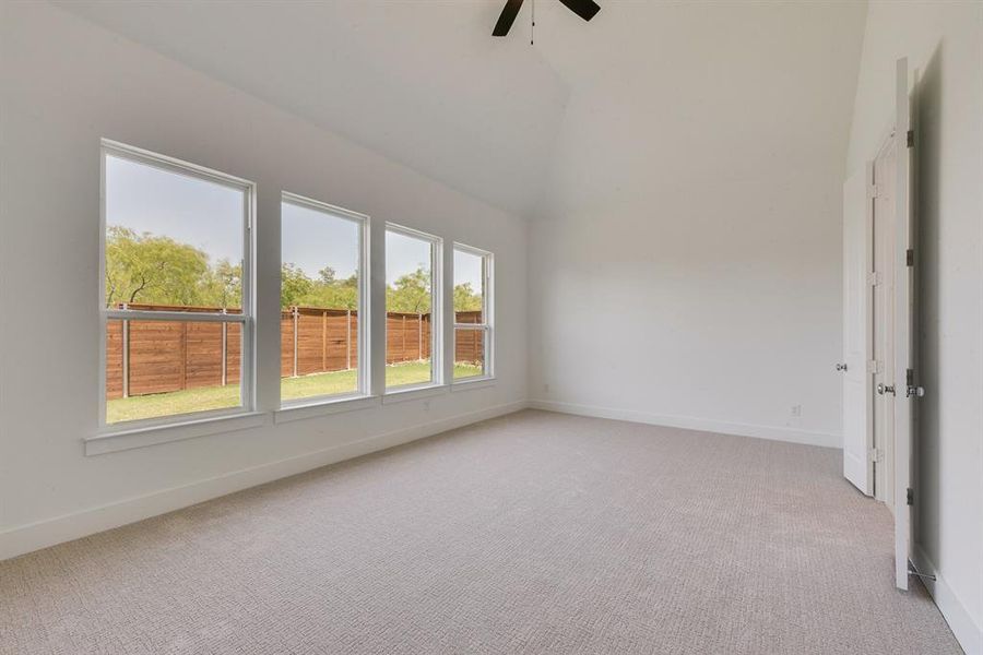 Empty room featuring light carpet, ceiling fan, and vaulted ceiling Empty room featuring light carpet, ceiling fan, and vaulted ceiling