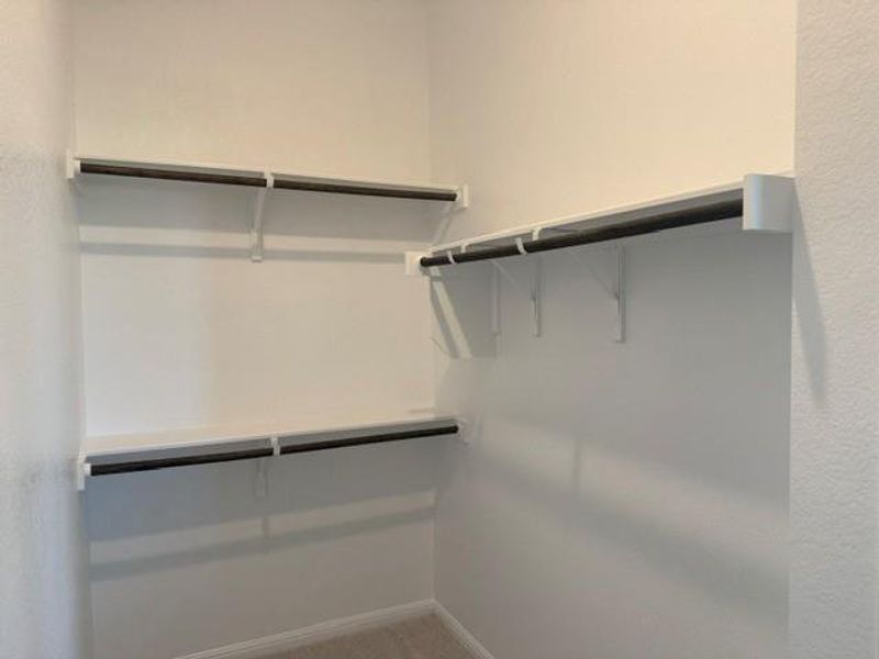 Walk-in closet featuring white shelving with integrated hanging rods