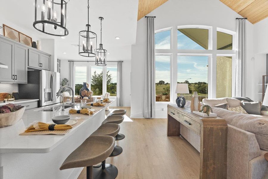 Kitchen featuring suspended lighting, a breakfast bar area, light wood-style floors, light stone countertops, and open floor plan