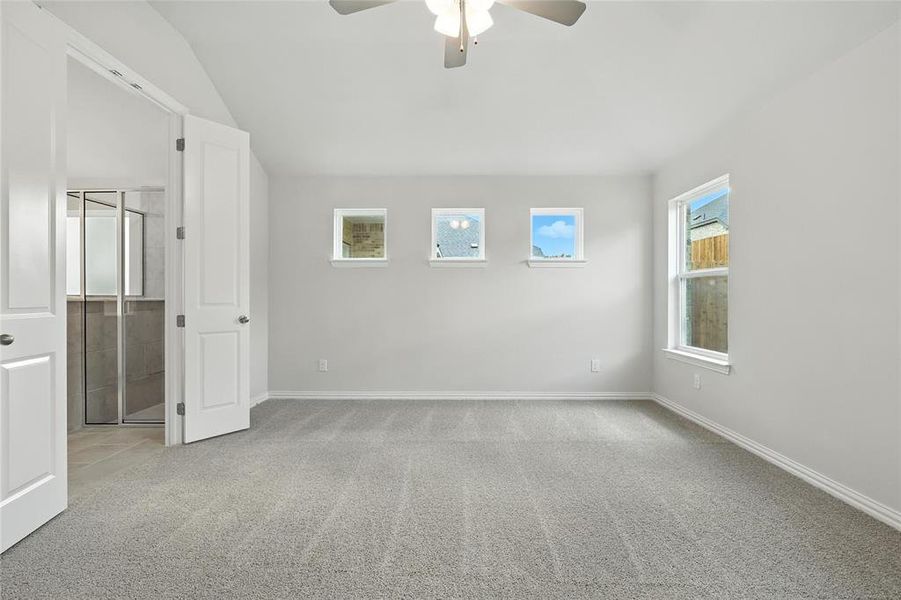 Unfurnished bedroom with a spacious closet, carpet flooring, a ceiling fan, and vaulted ceiling