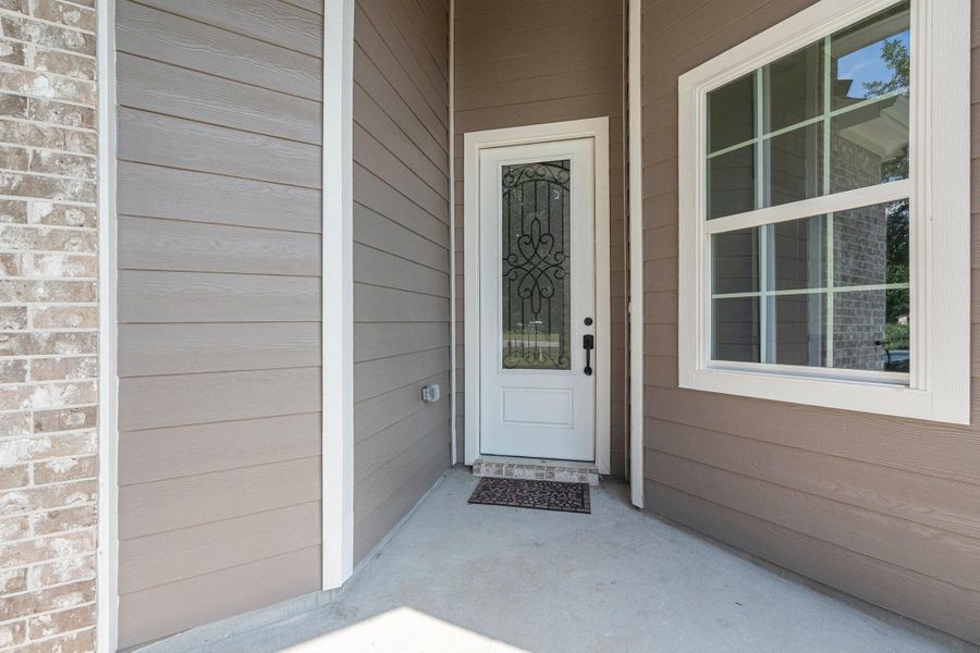 This photo shows a welcoming front entryway with a decorative glass door and adjacent window, framed by light brown siding and brick accents. This photo shows a welcoming front entryway with a decorative glass door and adjacent window, framed by light brown siding and brick accents.