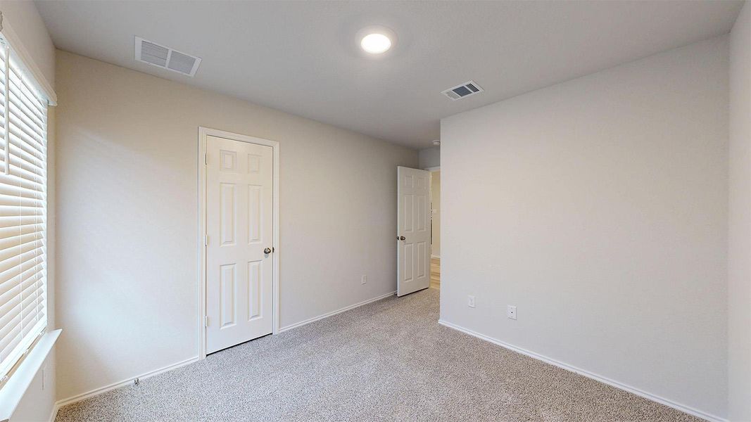 A well-proportioned bedroom offers carpet flooring and ample wall space for personalized decor.