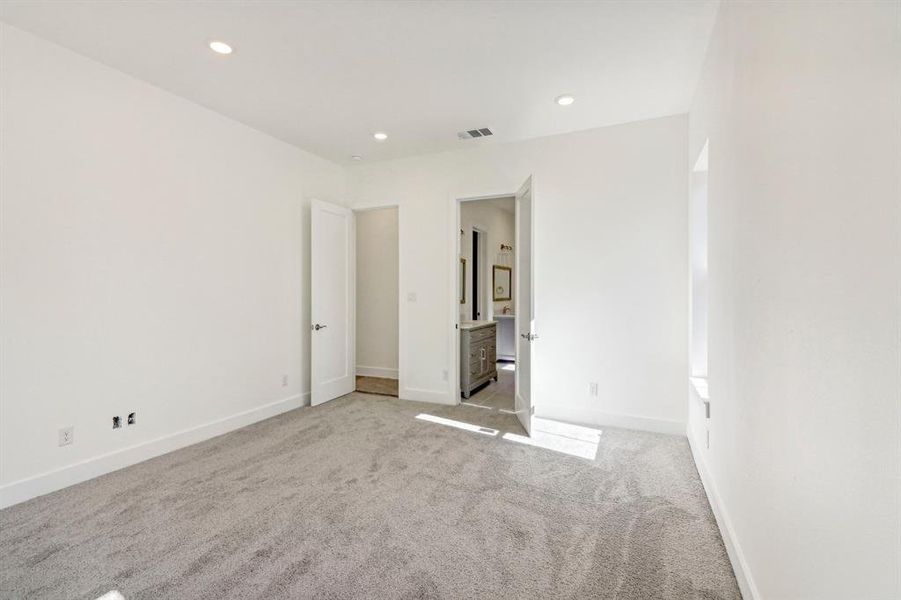 Unfurnished bedroom with light colored carpet, connected bathroom, and recessed lighting