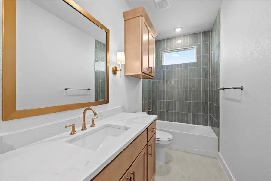 Bathroom featuring vanity, shower / washtub combination, light tile patterned floors, and a textured wall Bathroom featuring vanity, shower / washtub combination, light tile patterned floors, and a textured wall