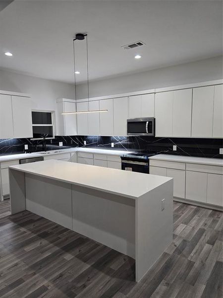 Kitchen featuring hanging light fixtures, dark hardwood / wood-style flooring, white cabinetry, range, and a center island