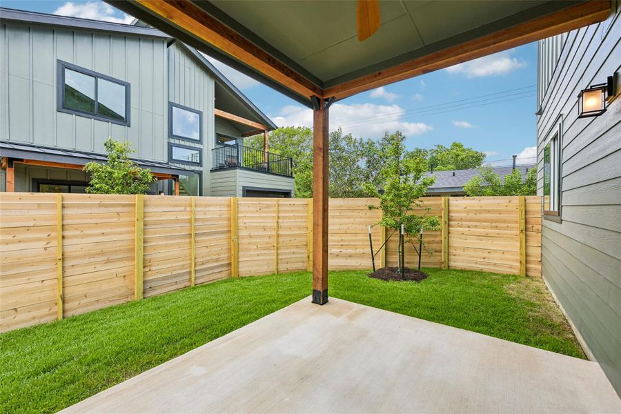 A private, grassy yard with a fresh cedar wood fence and an inviting concrete patio awaits.