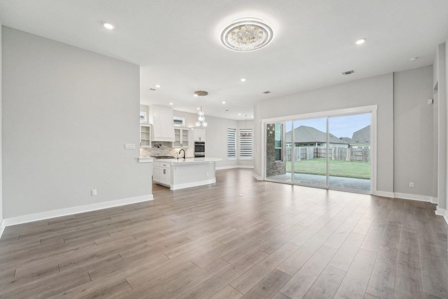 Unfurnished living room with recessed lighting, light wood-type flooring, baseboards, and a sink Unfurnished living room with recessed lighting, light wood-type flooring, baseboards, and a sink