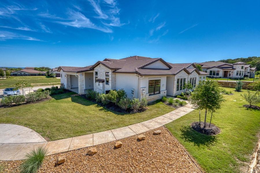 View of front of house featuring stone siding, stucco siding, a tile roof, and a front lawn