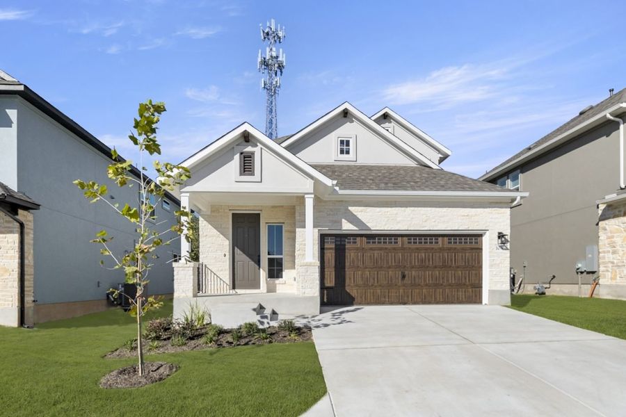 Front exterior of two-story house with a brown garage door with a driveway and green landscape. Front exterior of two-story house with a brown garage door with a driveway and green landscape.