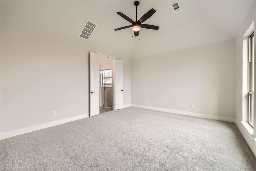 Empty room featuring a ceiling fan, carpet floors, high vaulted ceiling, and visible vents Empty room featuring a ceiling fan, carpet floors, high vaulted ceiling, and visible vents