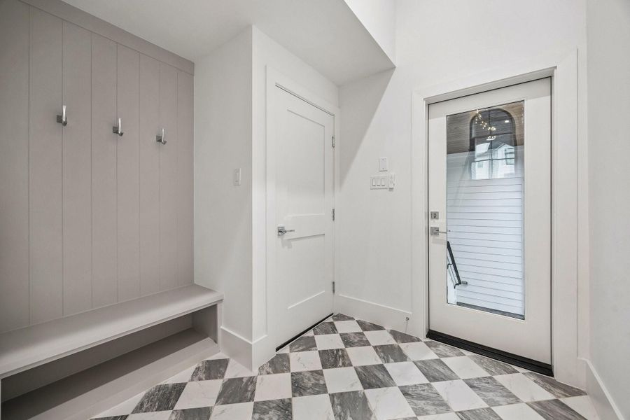 MUD Area off of the garage and the back patio with a 24 x 24 Checkerboard Matte Porcelain Tile in Calcutta and Amani Grey.  There is also a built-in bench and hooks.