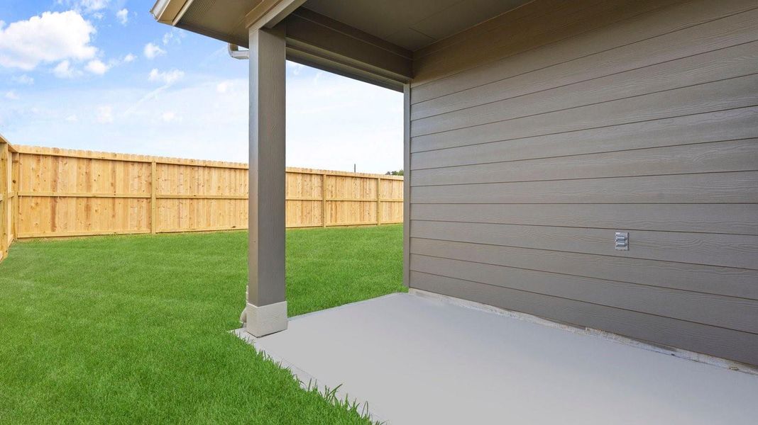 Outdoor covered patio with seating area overlooking a well-maintained lawn, perfect for relaxation.