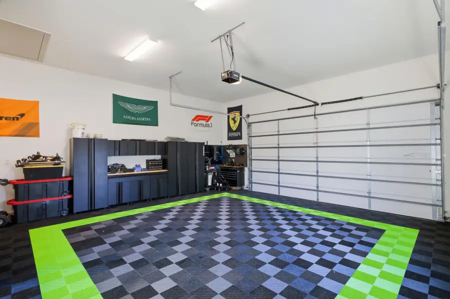The garage features a checkered floor with a distinct green border, an automatic garage door opener, and extensive built-in cabinetry along one wall