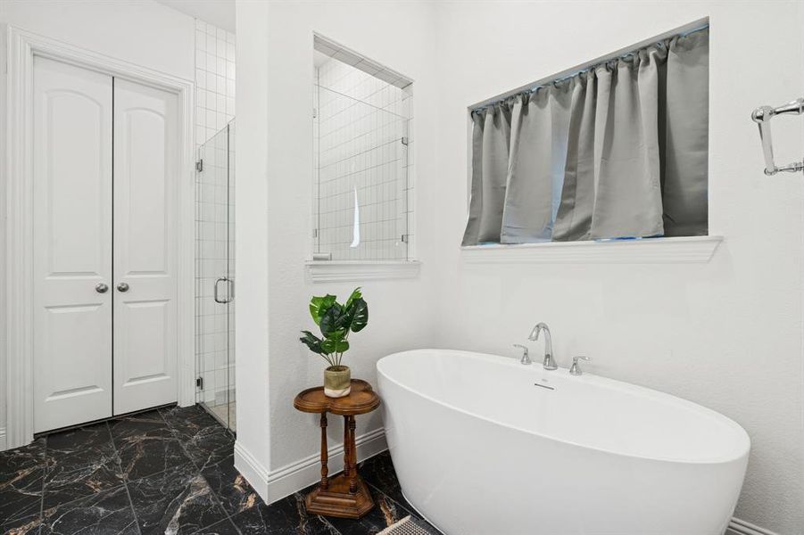 Bathroom with a freestanding bath, a shower stall, and dark marble finish floors Bathroom with a freestanding bath, a shower stall, and dark marble finish floors