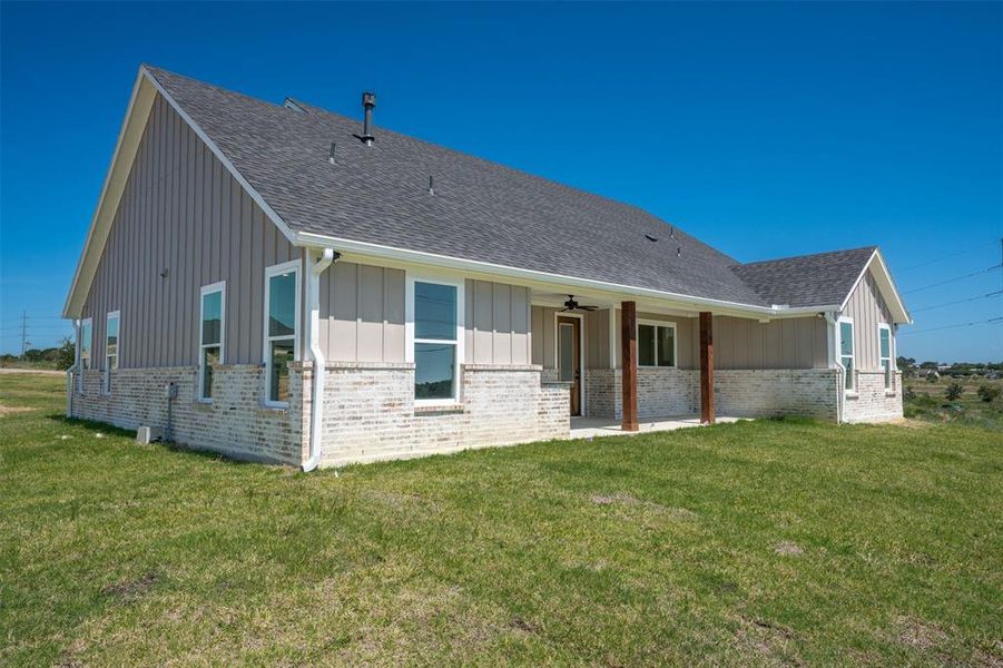 Back of property featuring board and batten siding, a lawn, and roof with shingles Back of property featuring board and batten siding, a lawn, and roof with shingles
