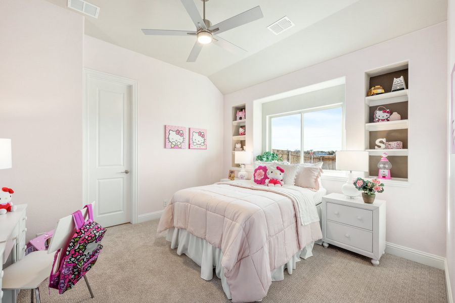 Children's bedroom with pink decor, vaulted ceiling, ceiling fan, built-in shelves, and white furniture on carpet flooring Children's bedroom with pink decor, vaulted ceiling, ceiling fan, built-in shelves, and white furniture on carpet flooring