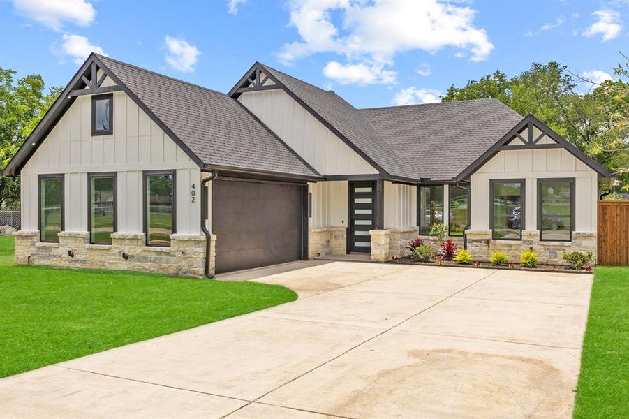 View of front of property with roof with shingles, stone siding, an attached garage, and concrete driveway View of front of property with roof with shingles, stone siding, an attached garage, and concrete driveway