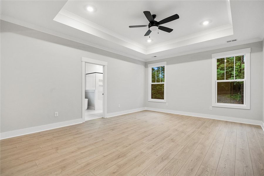 A spacious primary bedroom features a tray ceiling A spacious primary bedroom features a tray ceiling