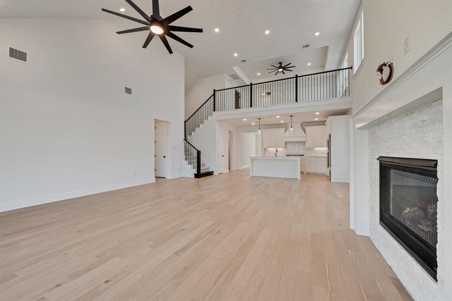 Unfurnished living room with a ceiling fan, a fireplace, light wood-style flooring, recessed lighting, and stairs Unfurnished living room with a ceiling fan, a fireplace, light wood-style flooring, recessed lighting, and stairs