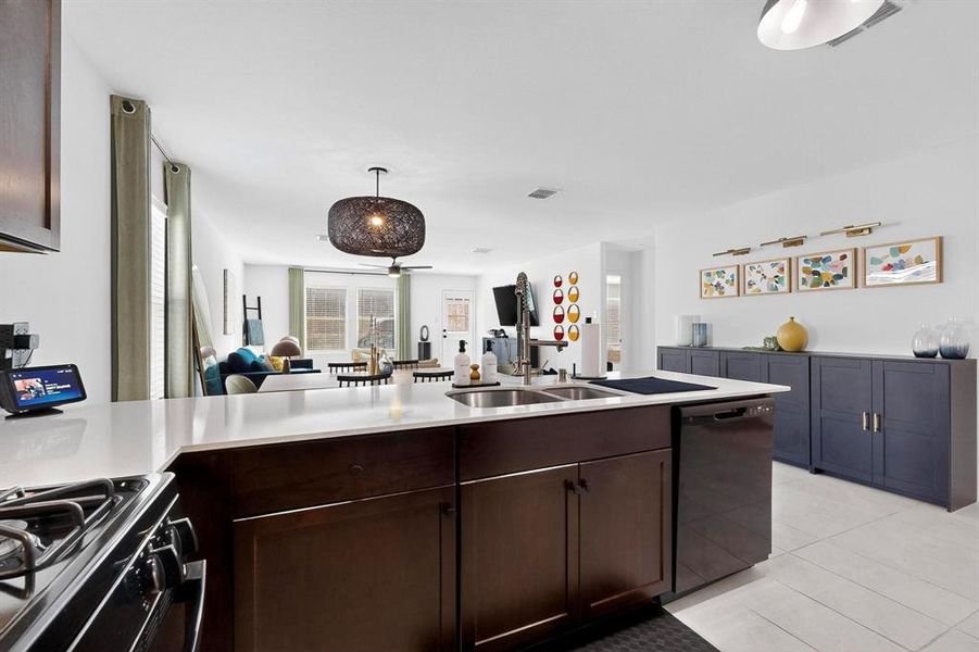 Kitchen featuring open floor plan, light tile patterned flooring, black appliances, dark brown cabinetry, and a peninsula Kitchen featuring open floor plan, light tile patterned flooring, black appliances, dark brown cabinetry, and a peninsula