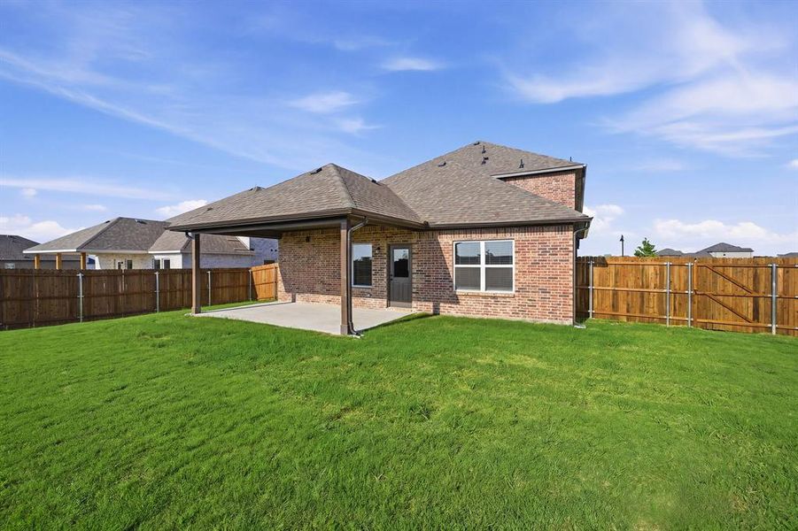 Expansive green lawn with a covered patio, brick exterior, and a privacy fence Expansive green lawn with a covered patio, brick exterior, and a privacy fence