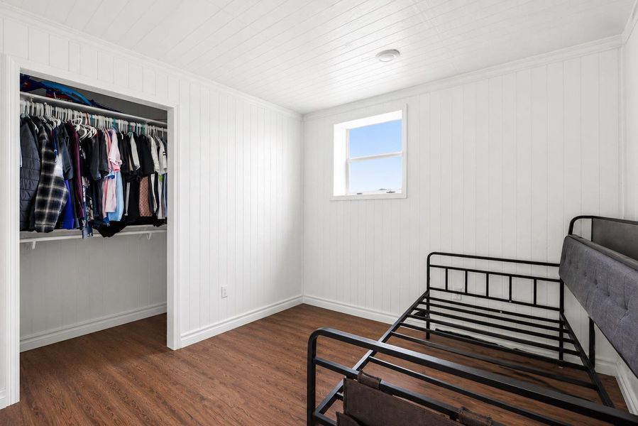 A well-lit bedroom features sturdy wood flooring and convenient closet storage.