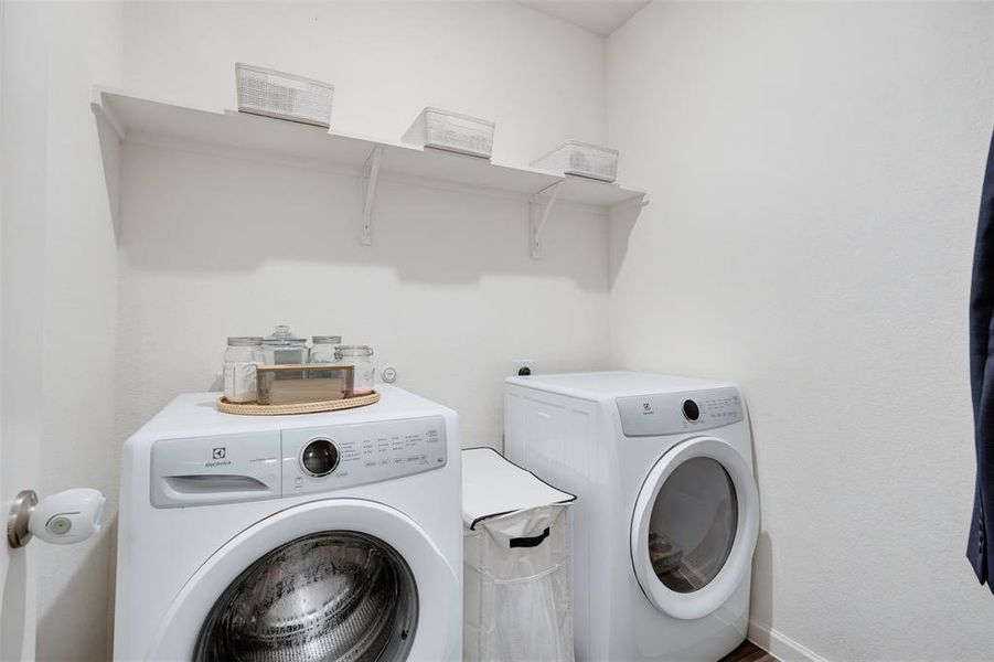 Dedicated laundry area featuring white walls and wood-finish flooring
